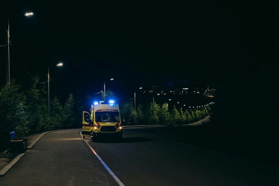 Ambulance with flashing lights on a rural road at night, ready for emergency response.