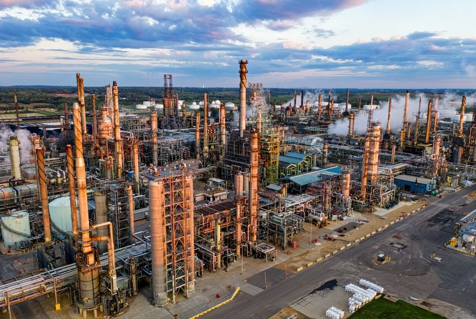 Oil refinery with flames against evening sky, illustrating energy supply concerns from Middle East attacks